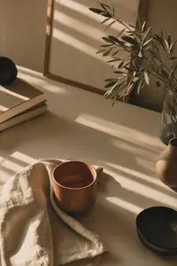 Late afternoon window light across a desk with a terracotta cup
